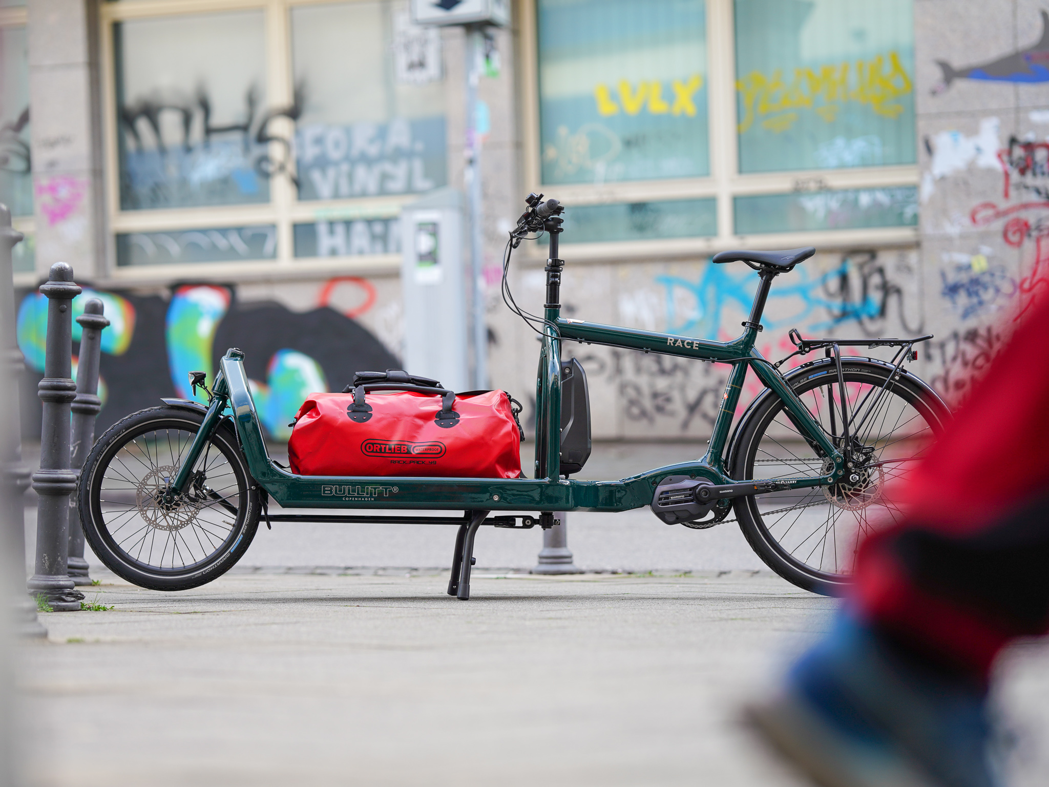 BULLITT Transportrad Race (dunkelgrün) mit einer wasserdichten Transporttasche von Ortlieb in rot
Foto: neomesh.